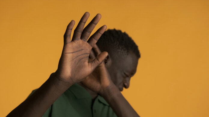 Jeune homme afro-américain effrayé posant devant l'appareil photo. Ne veut pas regarder l'expression.